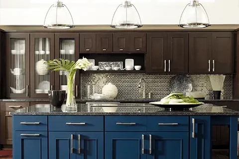 Modern kitchen with dark wood cabinets, blue island, and decorative lighting.