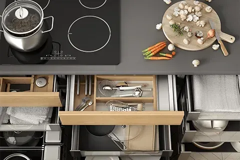 Overhead view of a modern kitchen countertop with a stove, drawers, and food preparation.