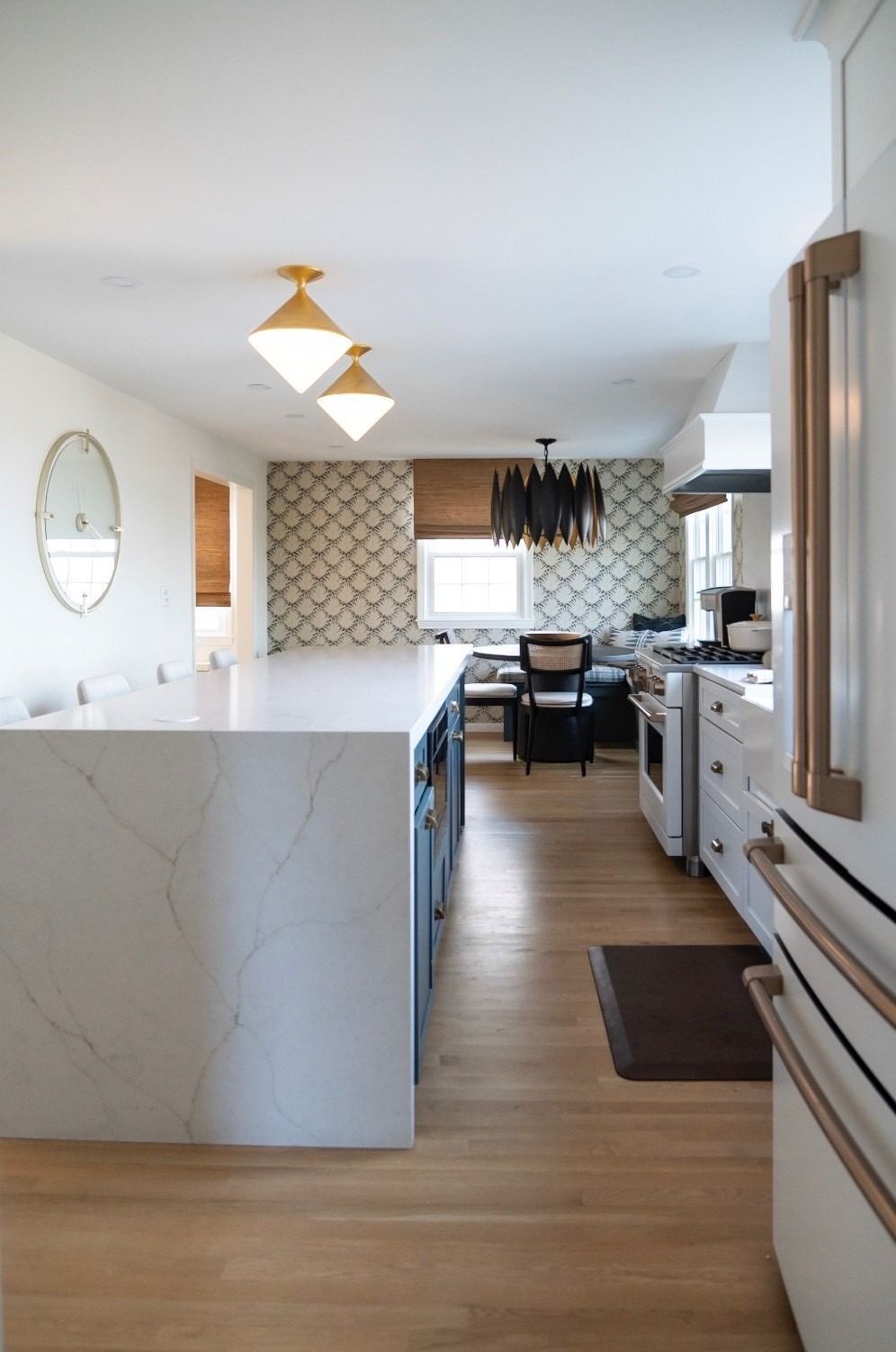 Modern kitchen with white island, wood floors, and geometric patterned wallpaper.