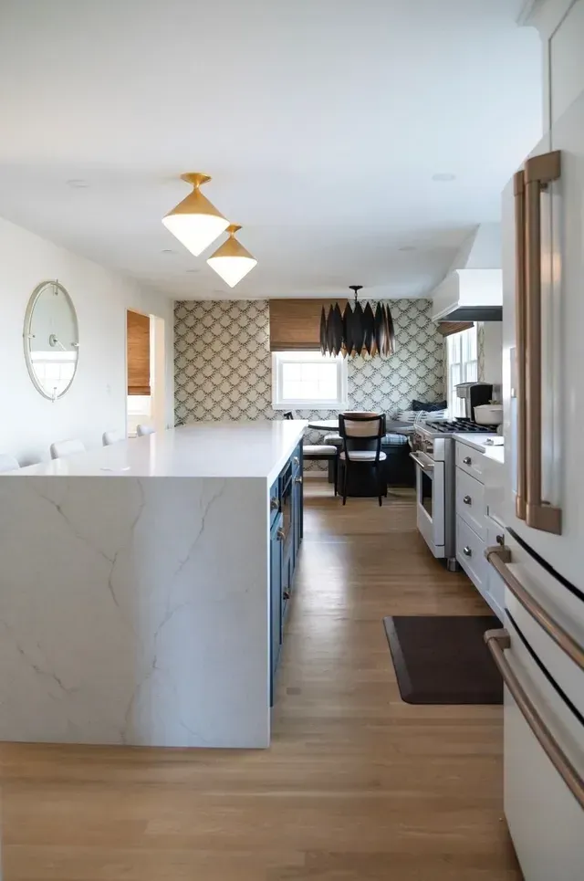 Kitchen with gray cabinets, stainless steel refrigerator, and range. White backsplash, granite countertops.