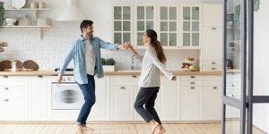 Couple dancing barefoot in a bright white kitchen with wooden countertops.