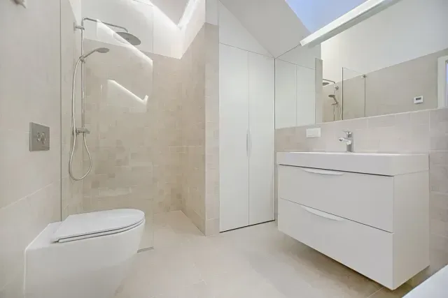 Kitchen cabinets with glass doors, white backsplash, countertop, and built-in lighting.