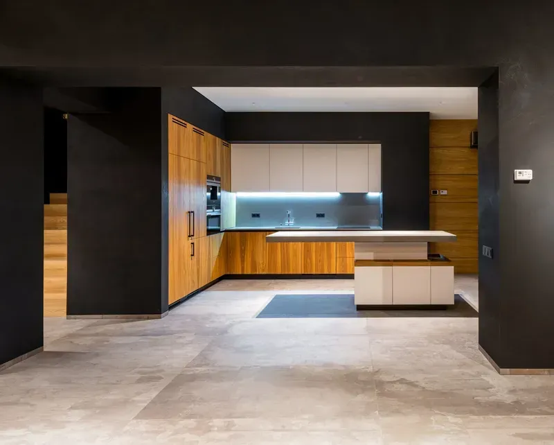 Modern kitchen with dark walls, wooden cabinets, a white countertop island, and tile flooring.