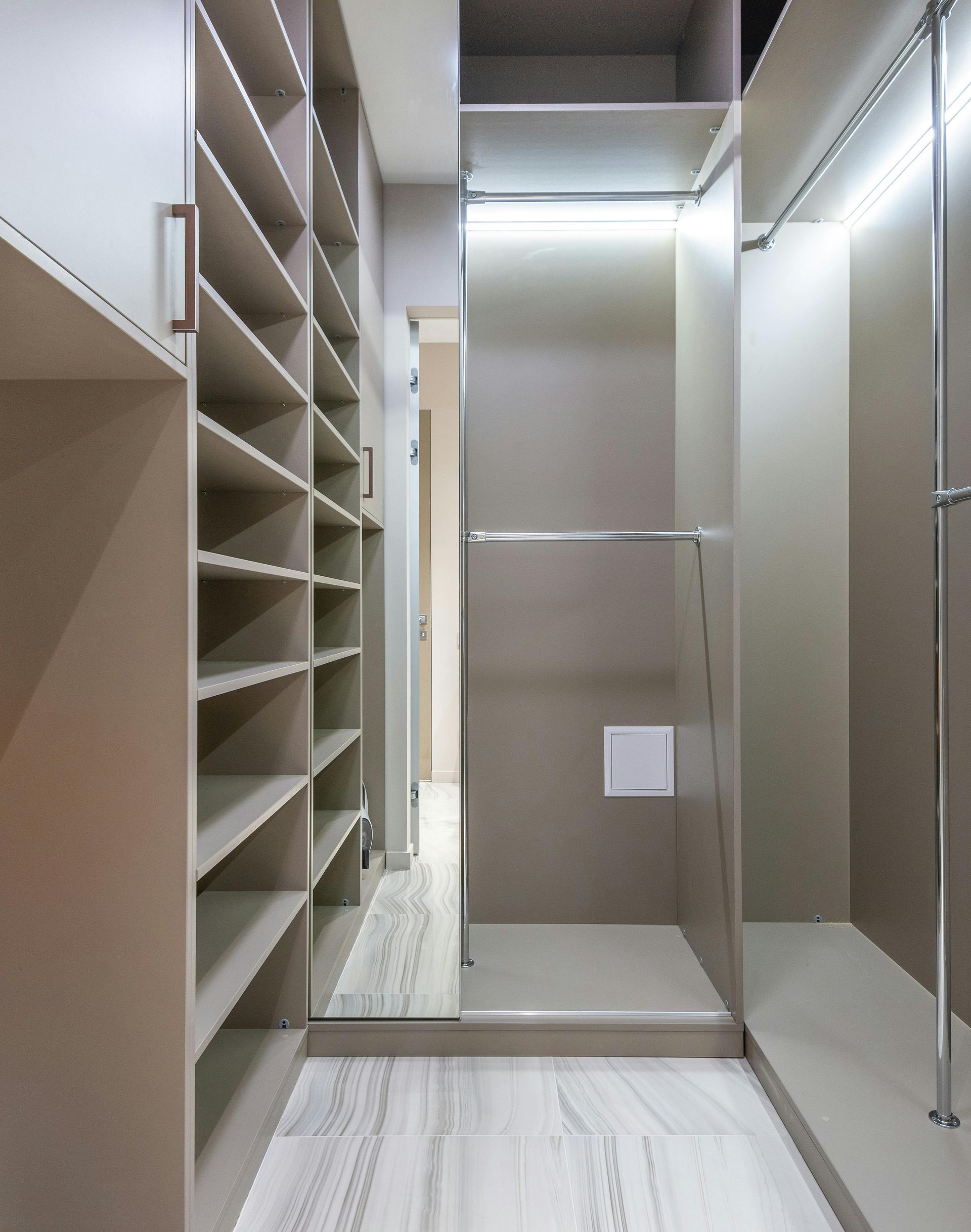 Empty walk-in closet with shelves and hanging rods. Neutral colors, recessed lighting.