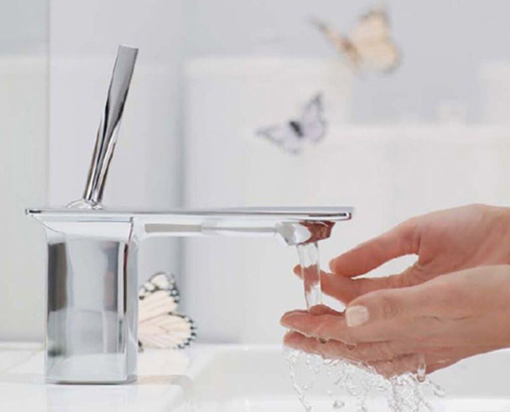 Hands washing under a modern chrome faucet in a bathroom, water flowing, butterflies.