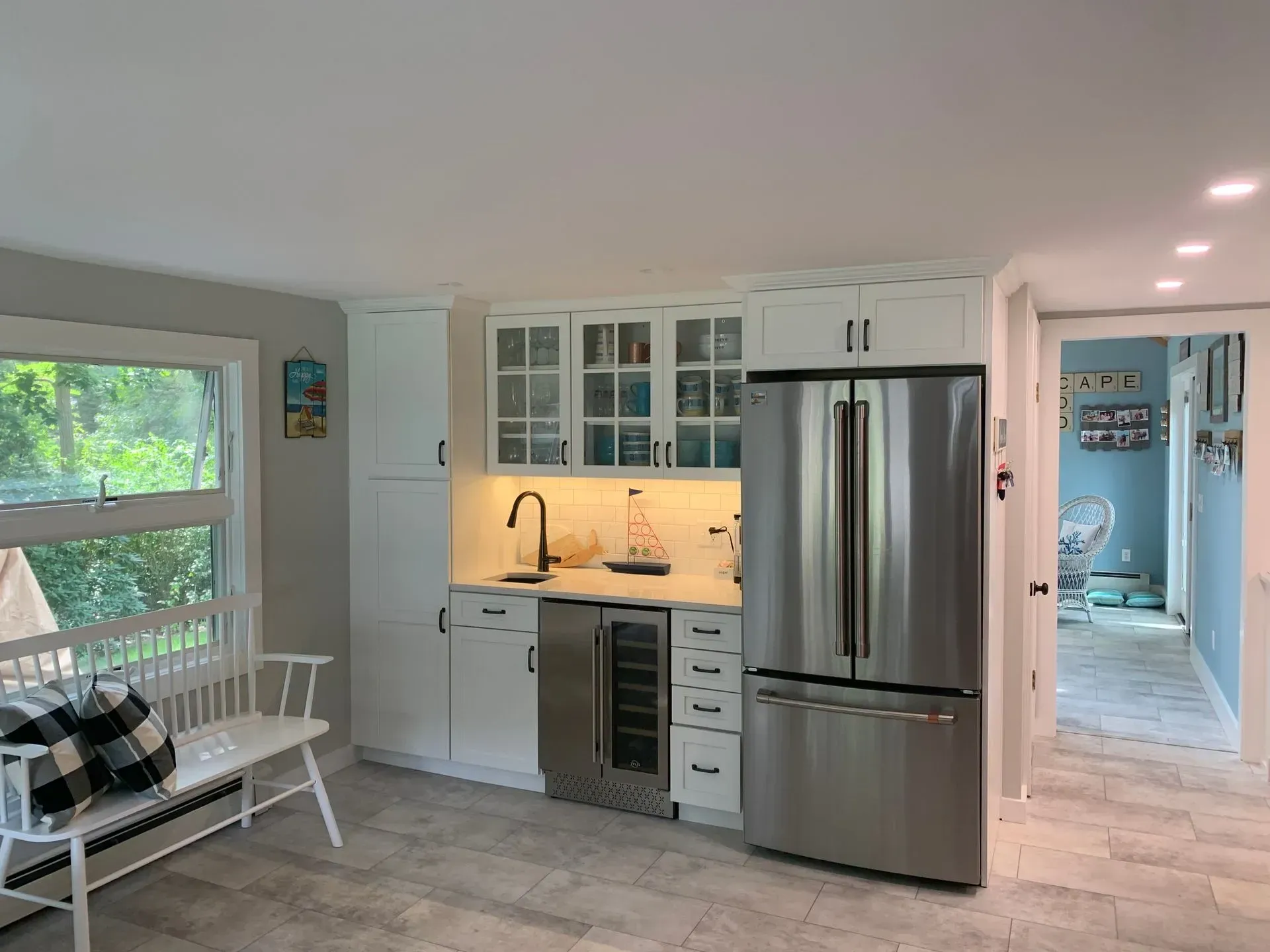 White kitchen area with a refrigerator, cabinets, a sink, and a wine cooler.