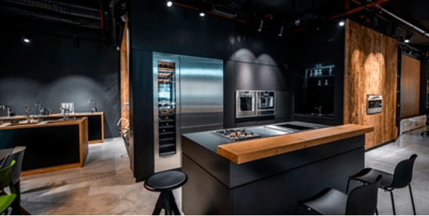Modern kitchen interior with dark cabinetry and stainless steel appliances. Features wood accents and a central island.