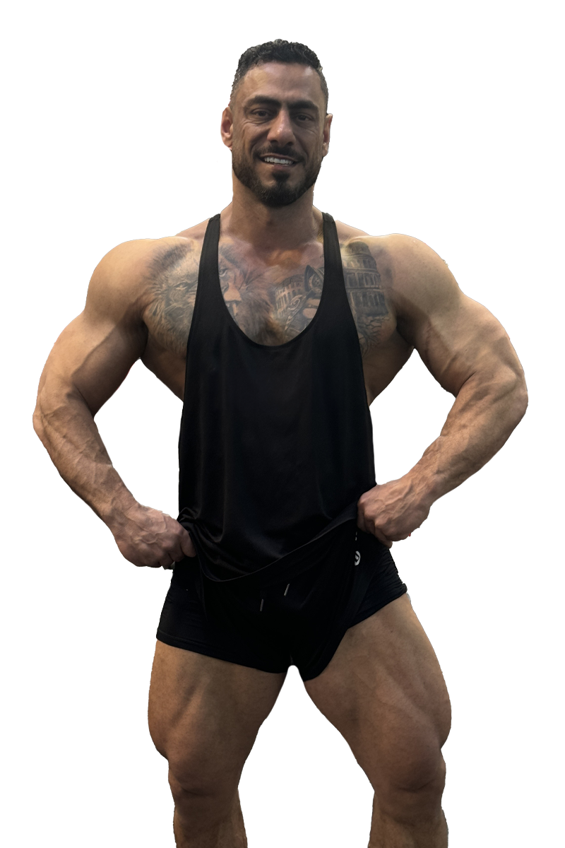 A man is standing with his hands on his hips wearing a black tank top and black shorts.