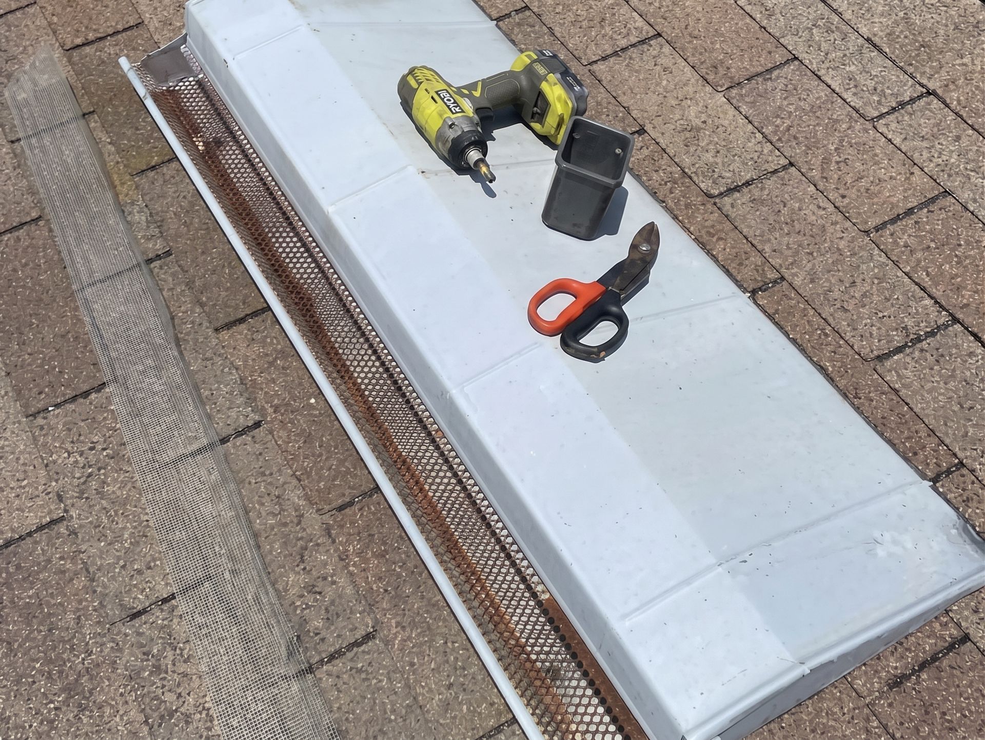 Roof vent installation with drill, battery, and snips on shingles