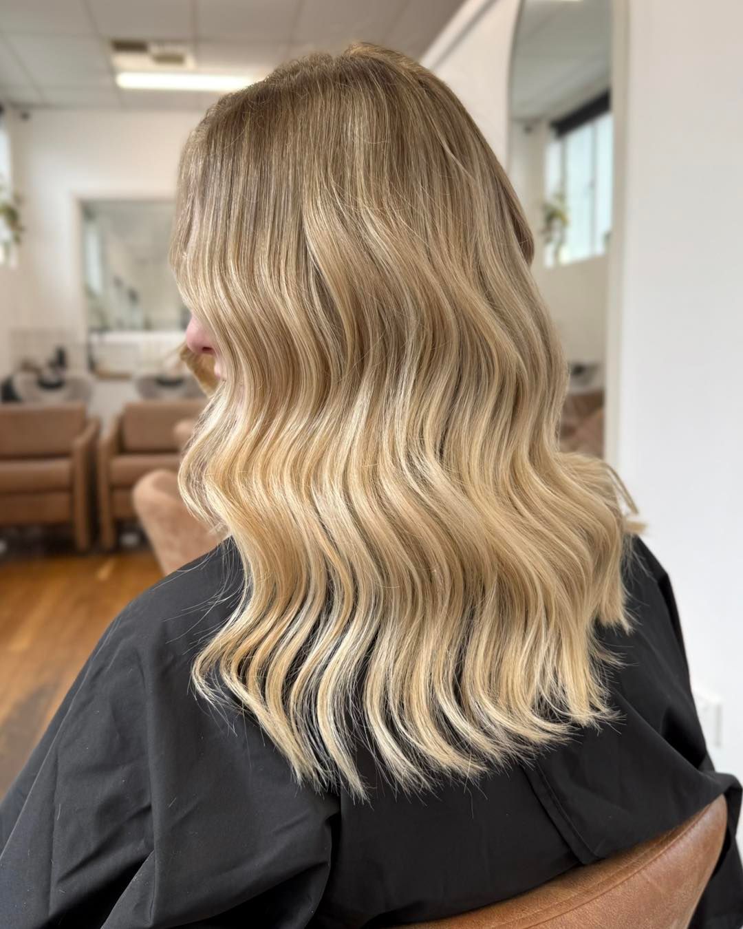 Blonde Wavy Shoulder-Length Hair with Dark Roots, Viewed from Behind in A Salon Chair — Pose Hair Design in Orange, NSW