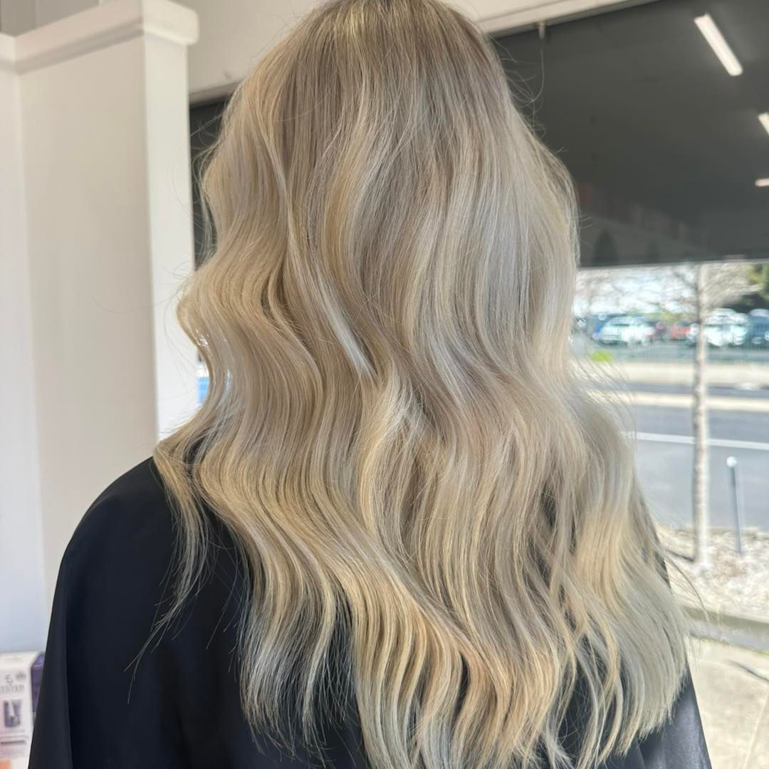 Blonde wavy hair viewed from behind in a salon, with a street visible through the window — Pose Hair Design in Orange, NSW