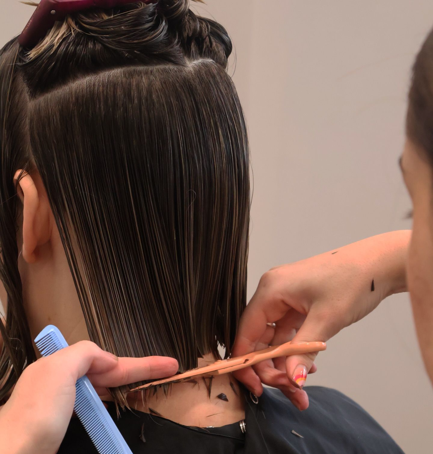 Hairdresser trimming wet dark hair at the nape with scissors and comb — Pose Hair Design in Orange, NSW