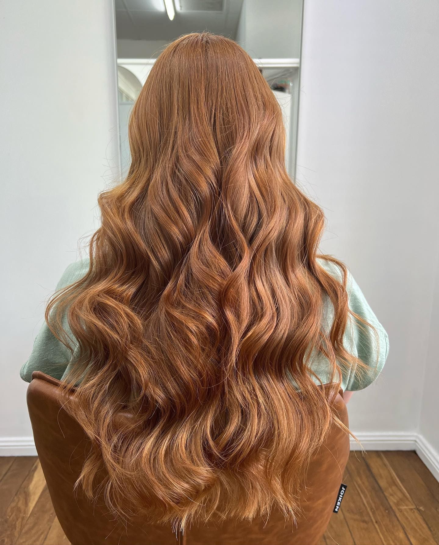 Woman with Long, Wavy Auburn Hair Shown from Behind in A Bright Room — Pose Hair Design in Orange, NSW