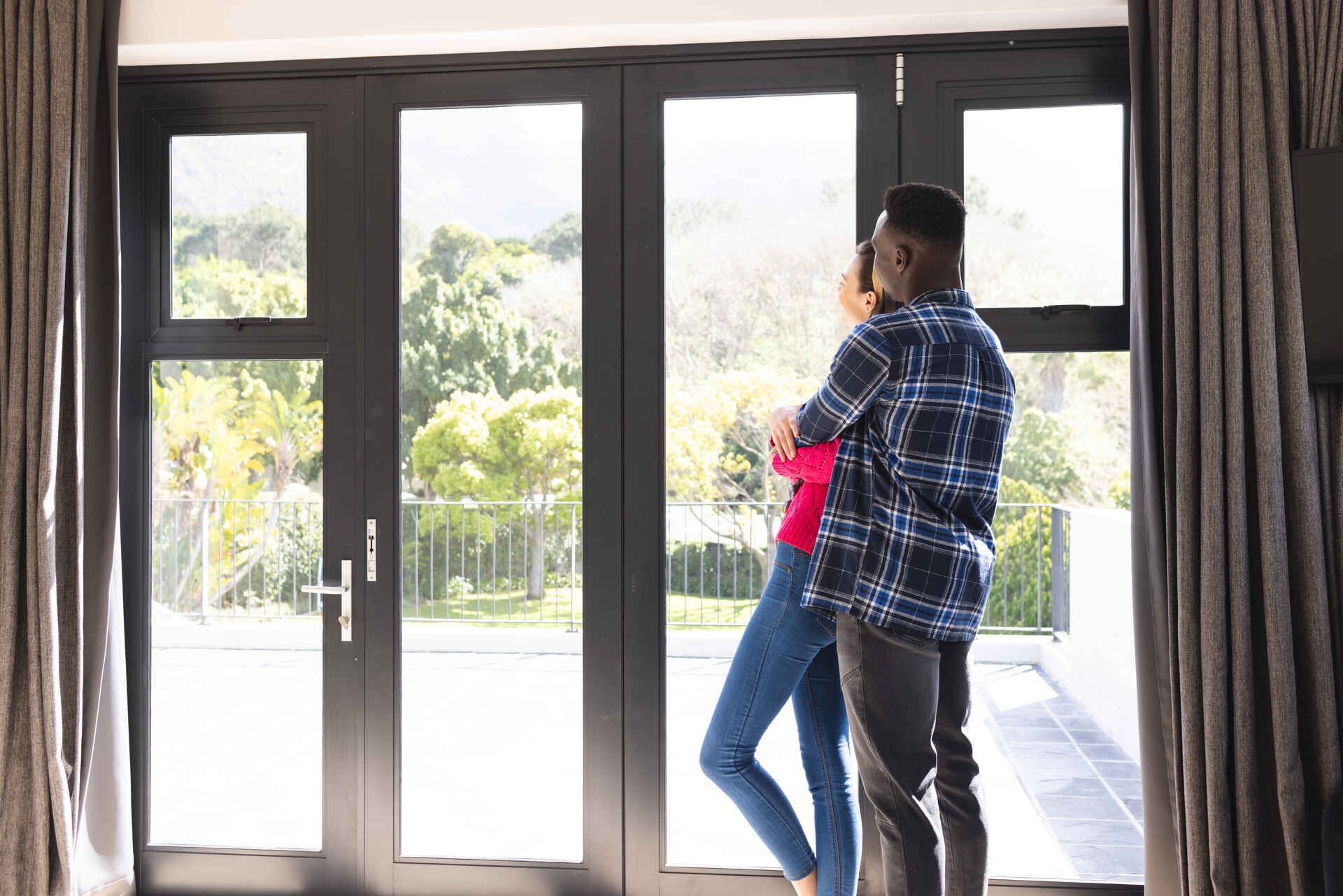 A man and a woman are standing in front of a large window.