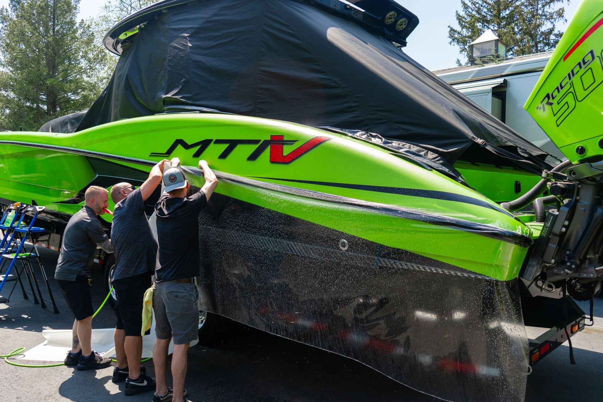 Men cleaning a neon green and black racing boat. 