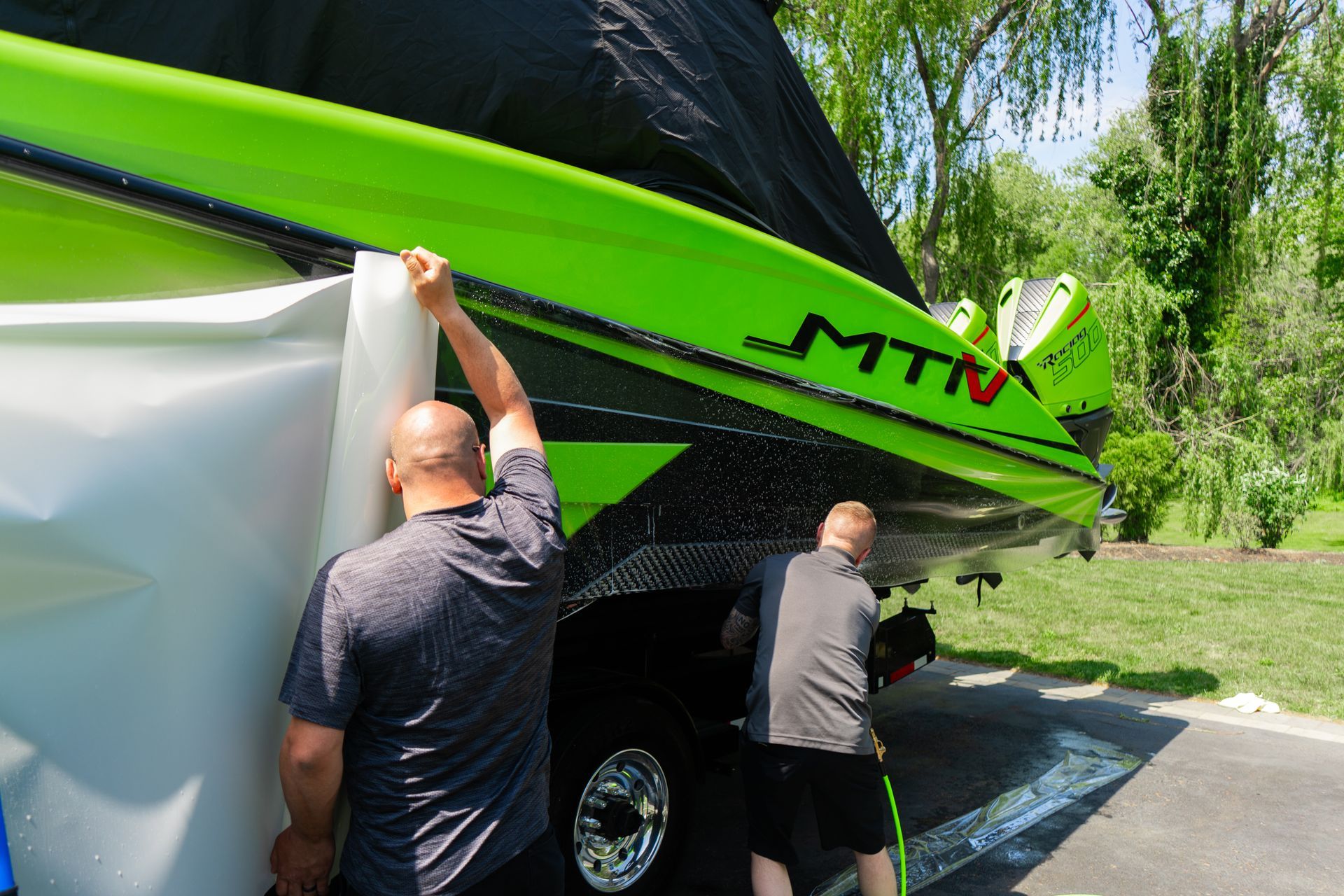 Two people washing a bright green boat with 