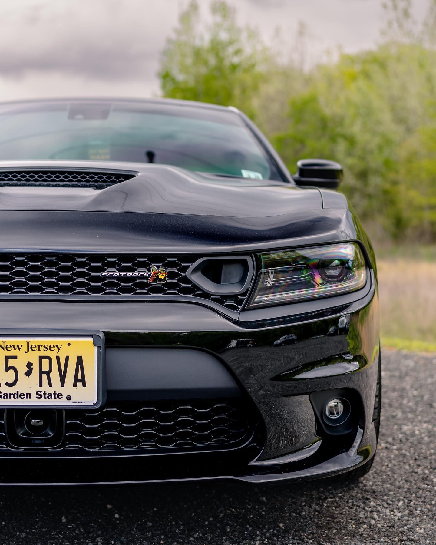 Black Dodge Charger with Jersey license plate parked outdoors.