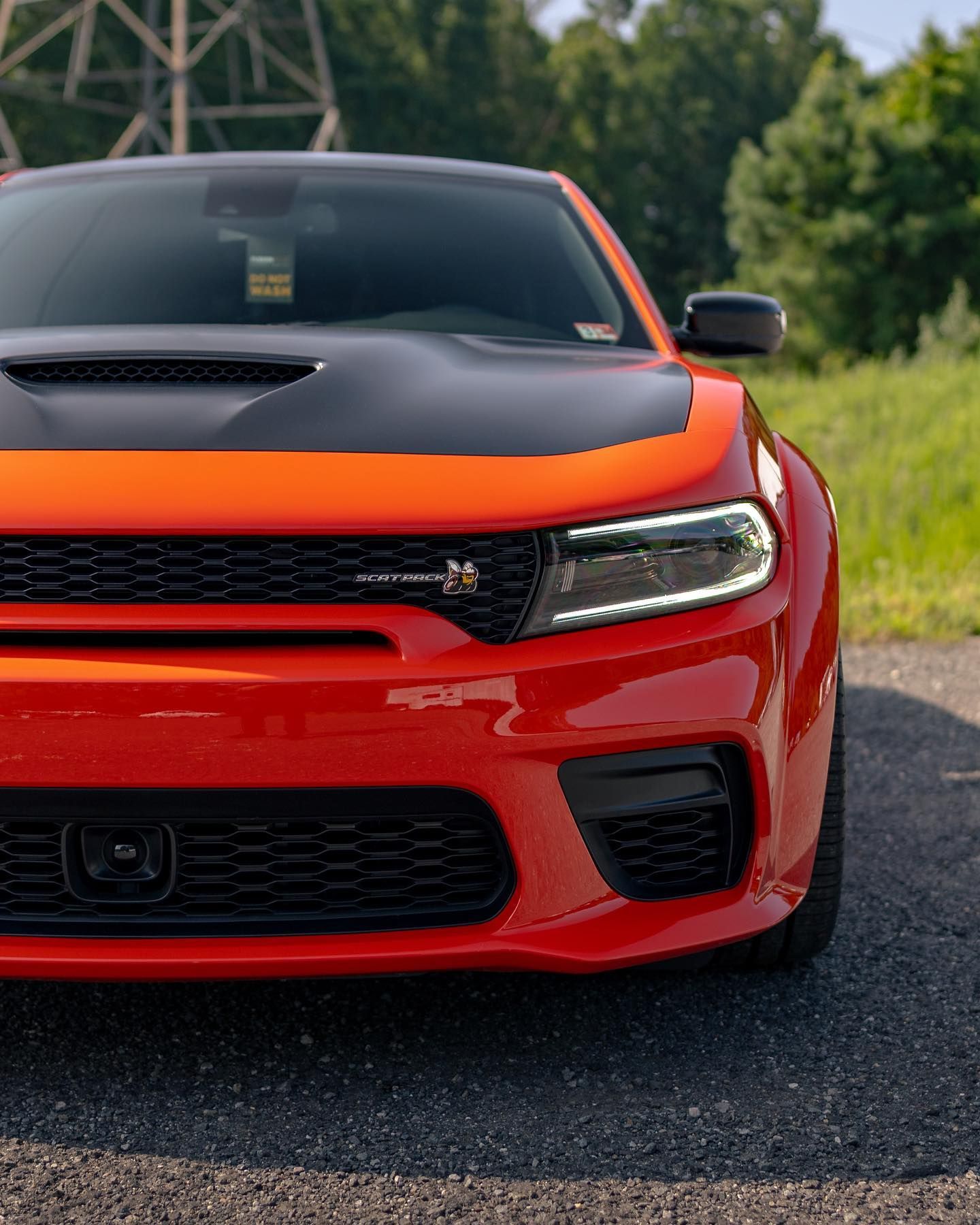 Orange and black Dodge Charger front view, parked on a road.