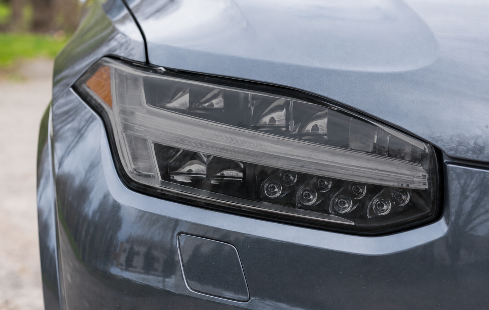 Silver Tesla car's front, including headlight, side mirror, and hood.