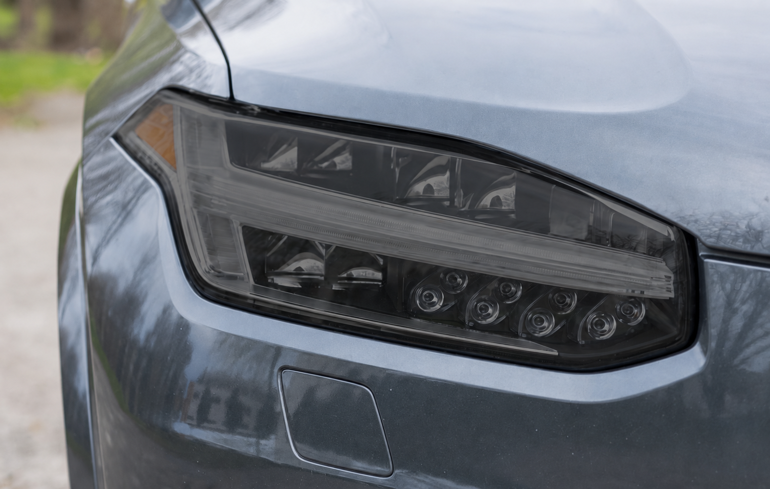 Silver Tesla car, front view, showing headlight, side mirror, and hood.
