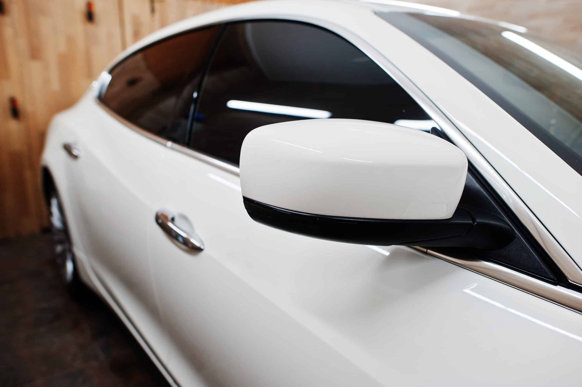 A white car is parked in front of a wooden wall