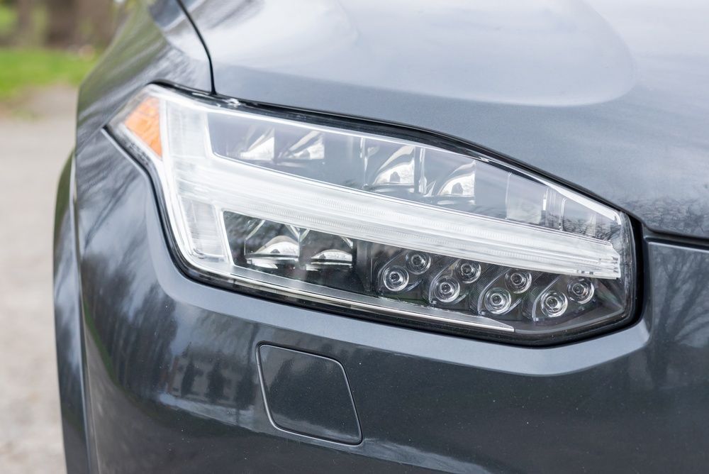 Silver Tesla car front, showing headlight, mirror, and hood.