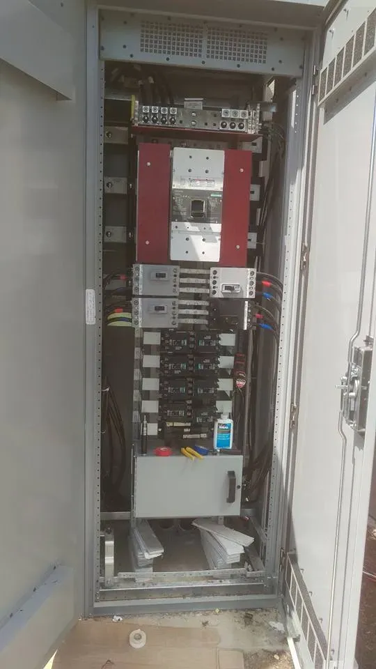 Open electrical control panel with red and gray components inside a metal cabinet.