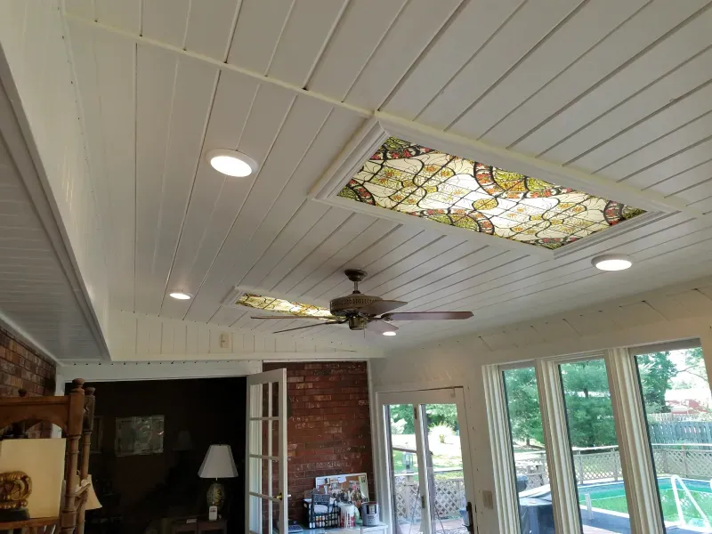 Sunroom ceiling with recessed lights, ceiling fan, and stained-glass skylights above glass doors and pool view