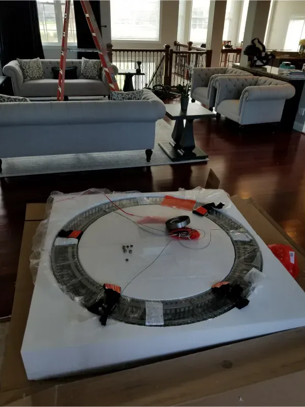 Toy race track on a living room table, with small cars on a circular track over a white base.