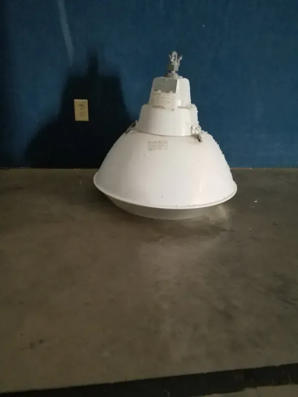 White hanging light fixture on a gray tabletop against a blue wall