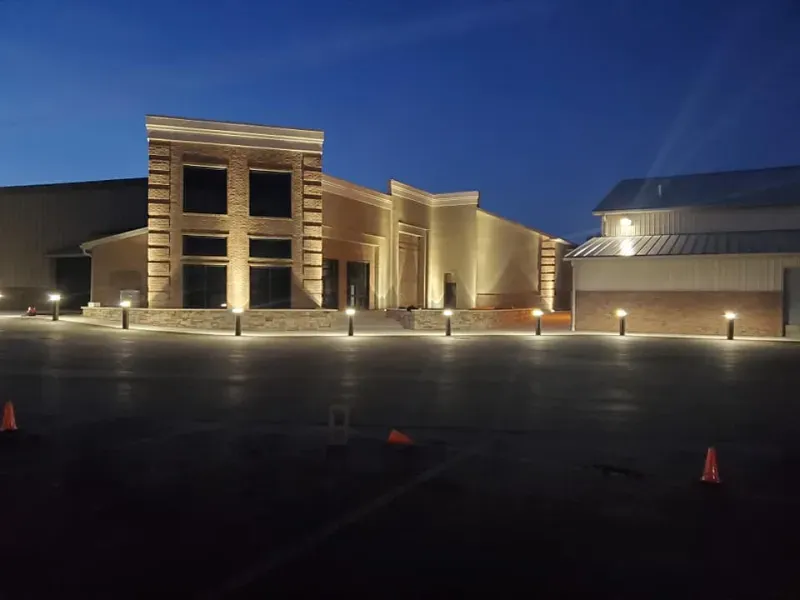 Lit building exterior at dusk with parking lot lights and a dark sky