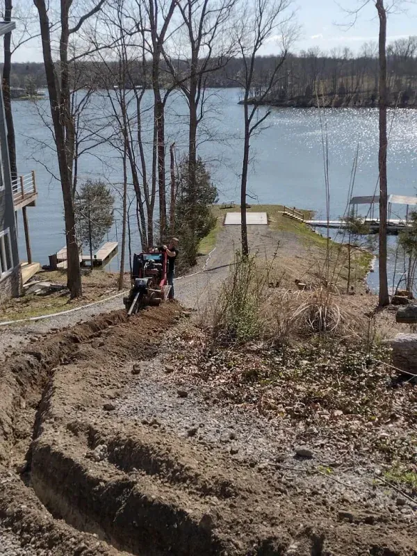 ATV on a steep dirt path beside a lake, with trees and docks in the background