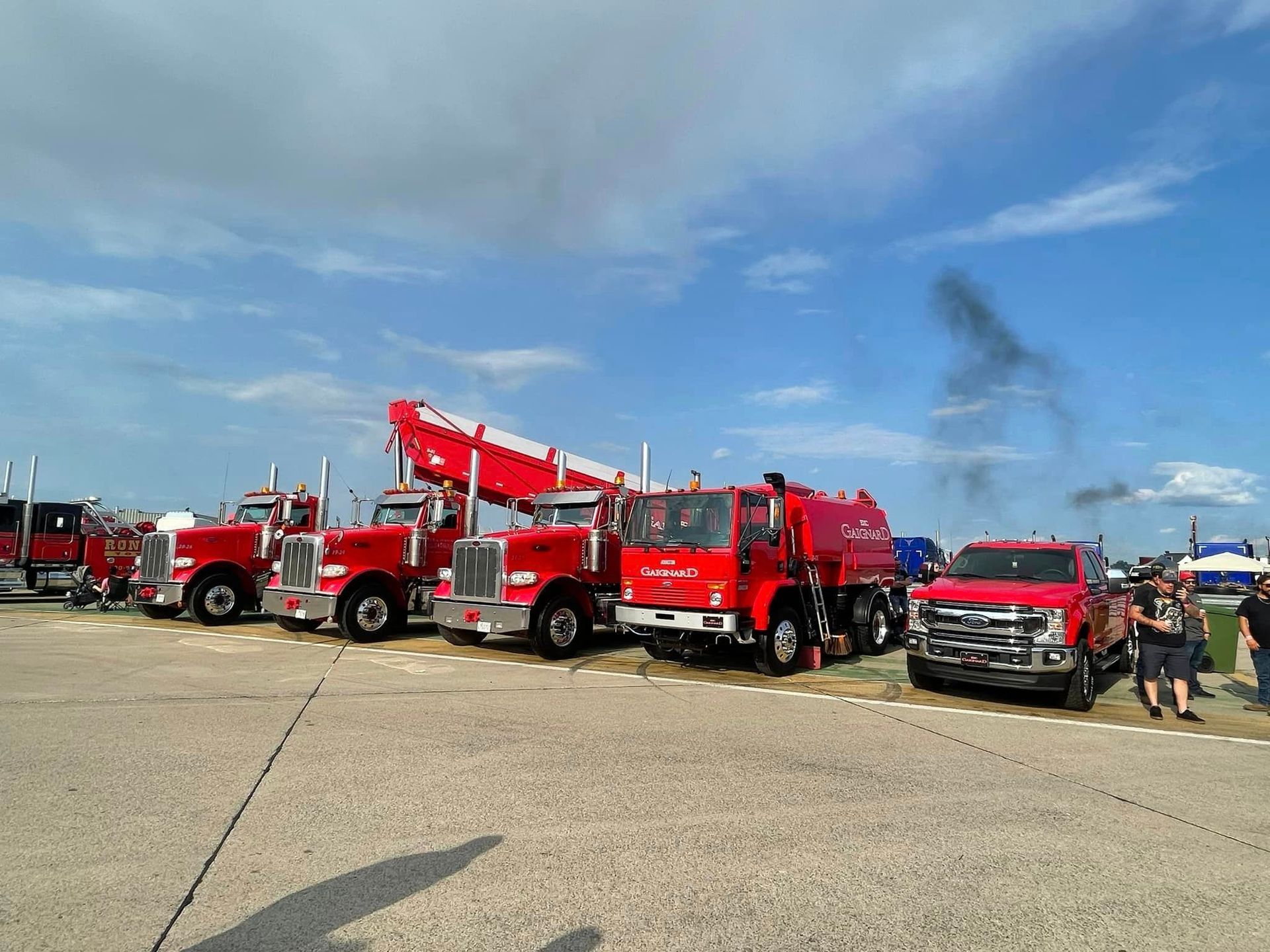 Camions de pompiers rouges stationnés à l'extérieur sous un ciel bleu. L'un d'eux est équipé d'une échelle déployée.