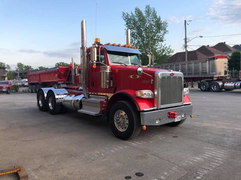 Camion-benne Peterbilt rouge stationné sur du béton.