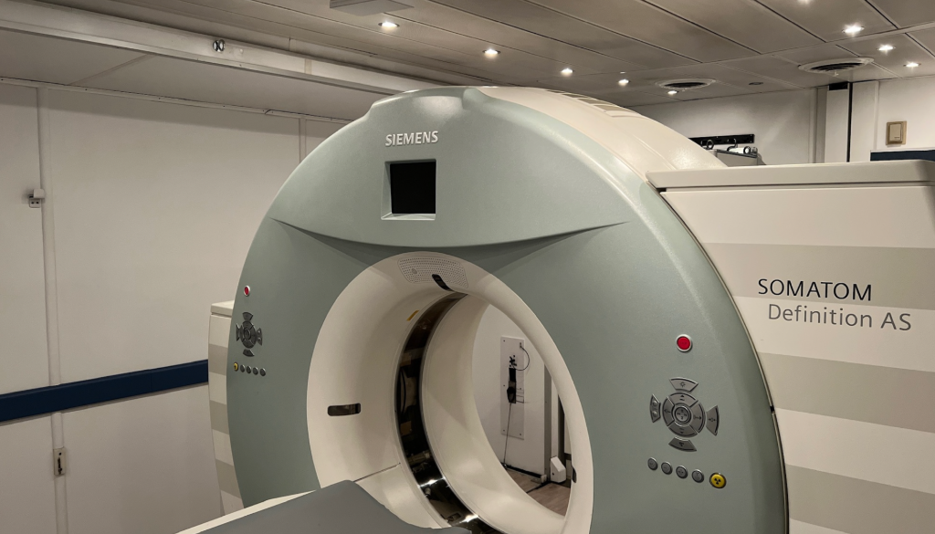 MRI scanner in a bright hospital room, white machine with circular opening