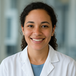 Smiling healthcare worker in a white coat against a softly blurred clinic background