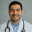 Smiling doctor in a white coat and stethoscope against a gray background