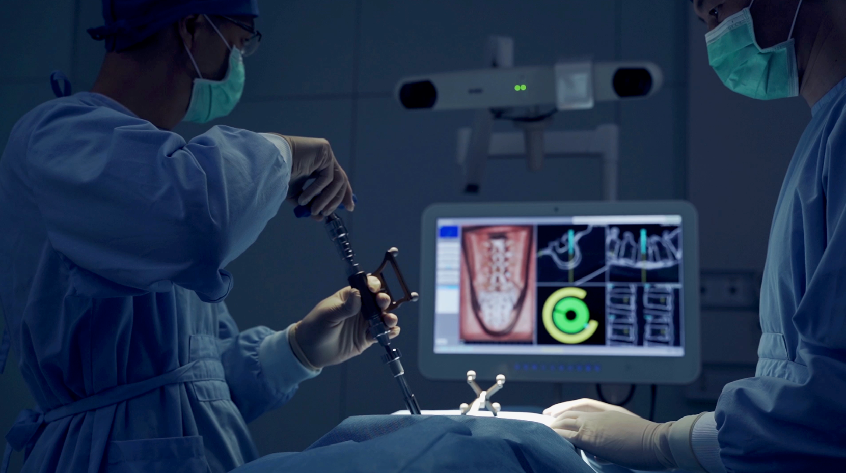 Dentist operating in a dark clinic beside a monitor showing teeth and scan images