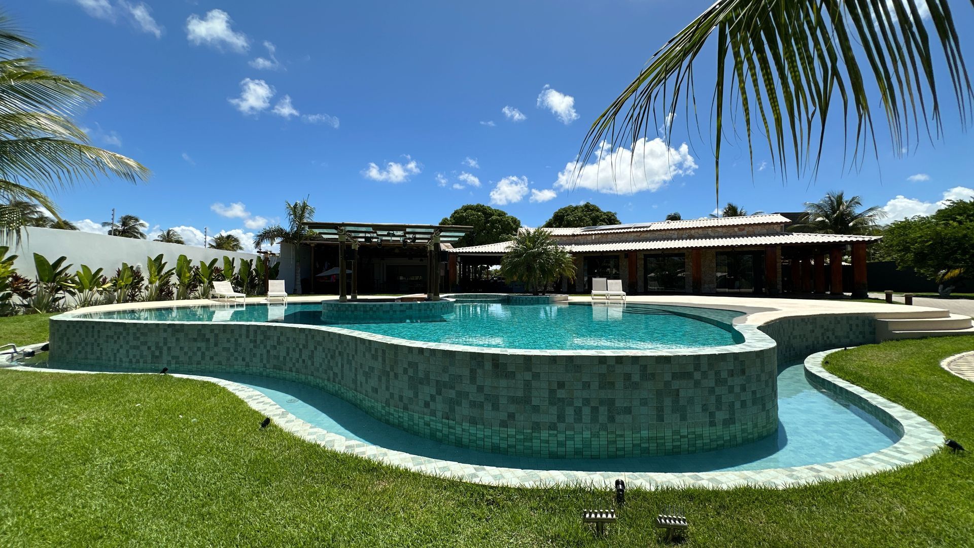 Há uma grande piscina no meio de um campo verdejante.