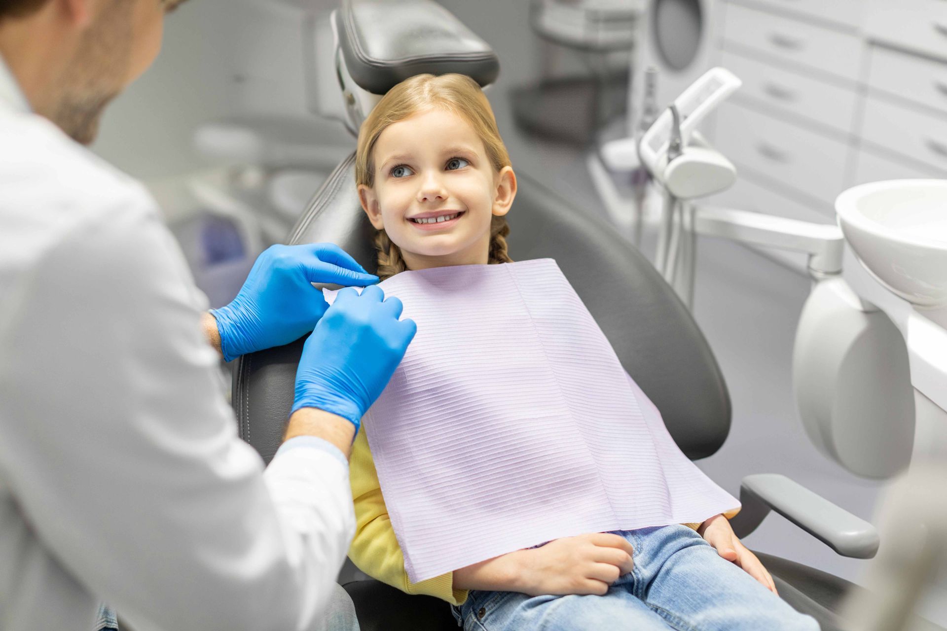 A dentist is preparing to conduct a procedure or checkup on a little female patient. A dentist is preparing to conduct a procedure or checkup on a little female patient.