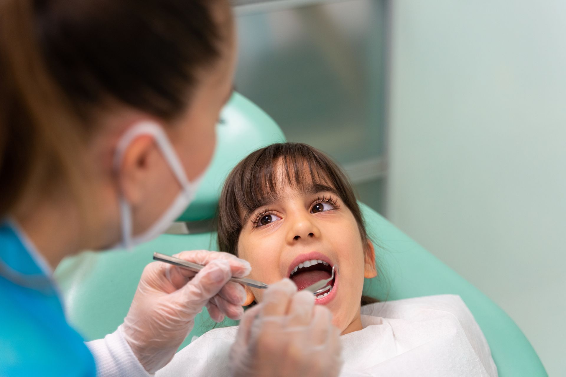 The dentist is examining the girl's teeth.