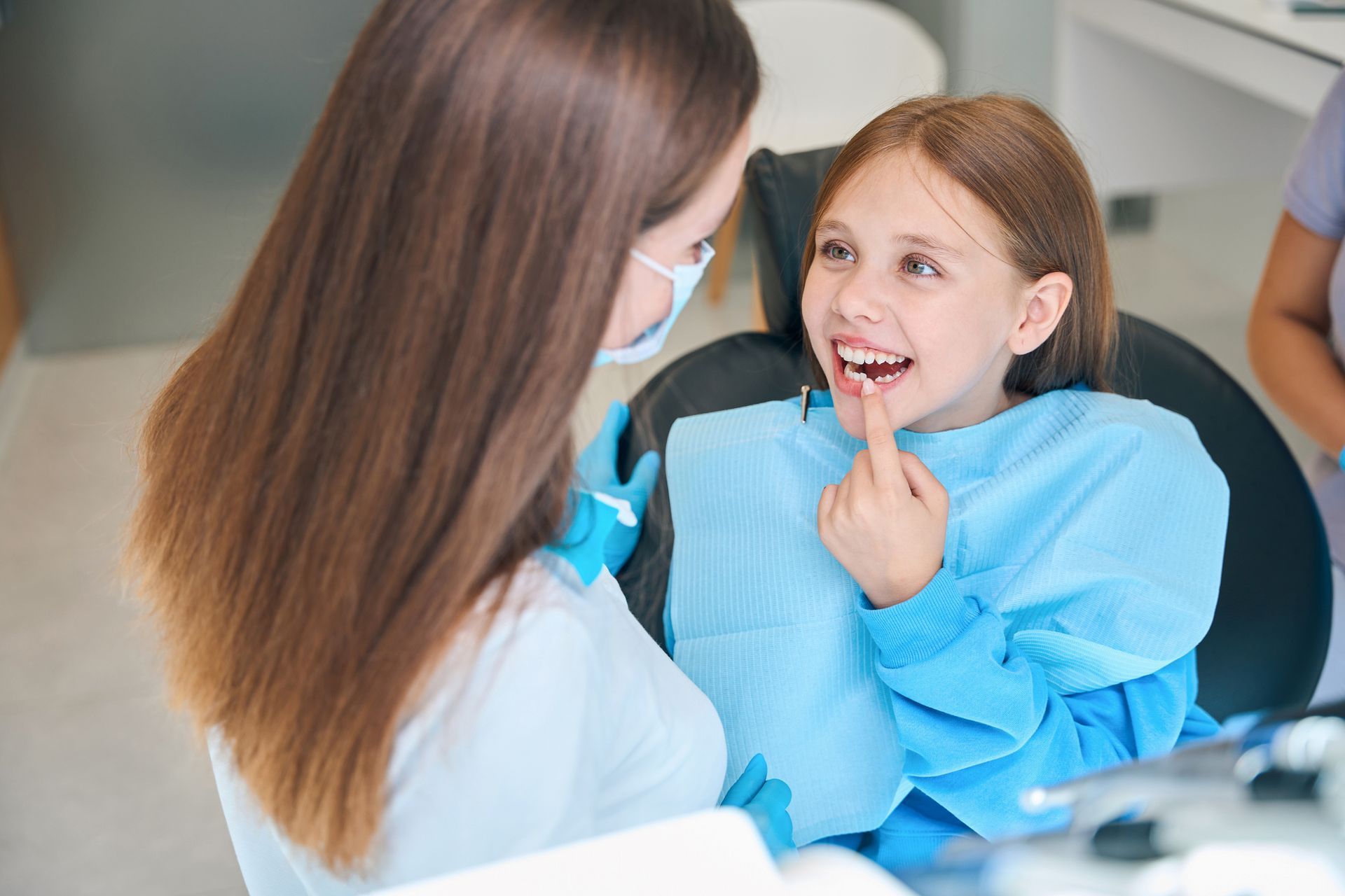 The girl shows her teeth to a dentist.