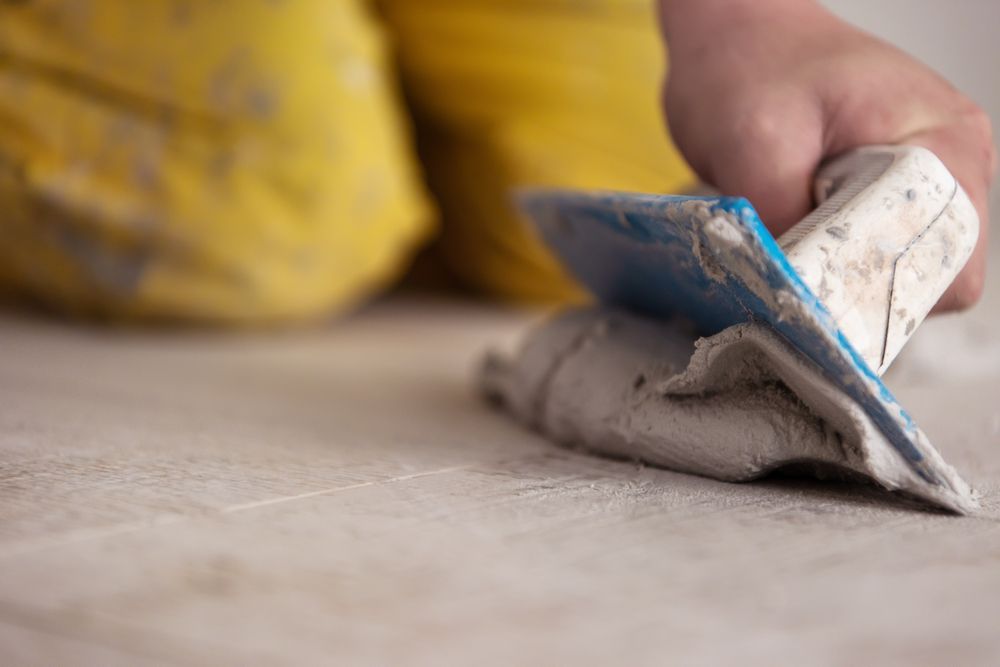 Hand Using a Trowel to Apply Plaster to a Surface — Tropic Tiling in Atherton, QLD
