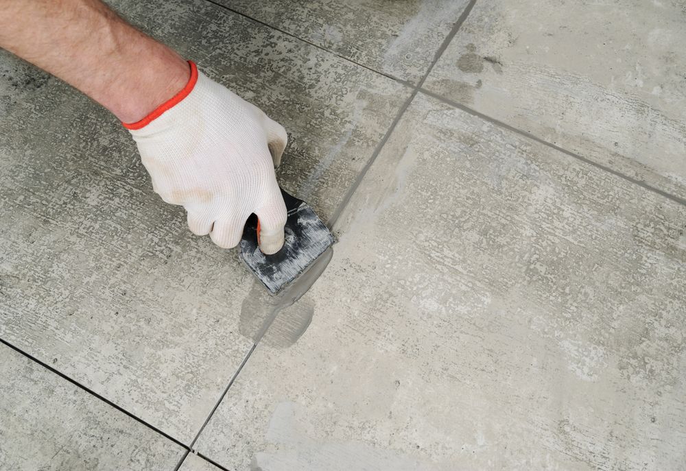 Gloved Hand Using a Sponge to Smooth Gray Grout — Tropic Tiling in Tolga, QLD