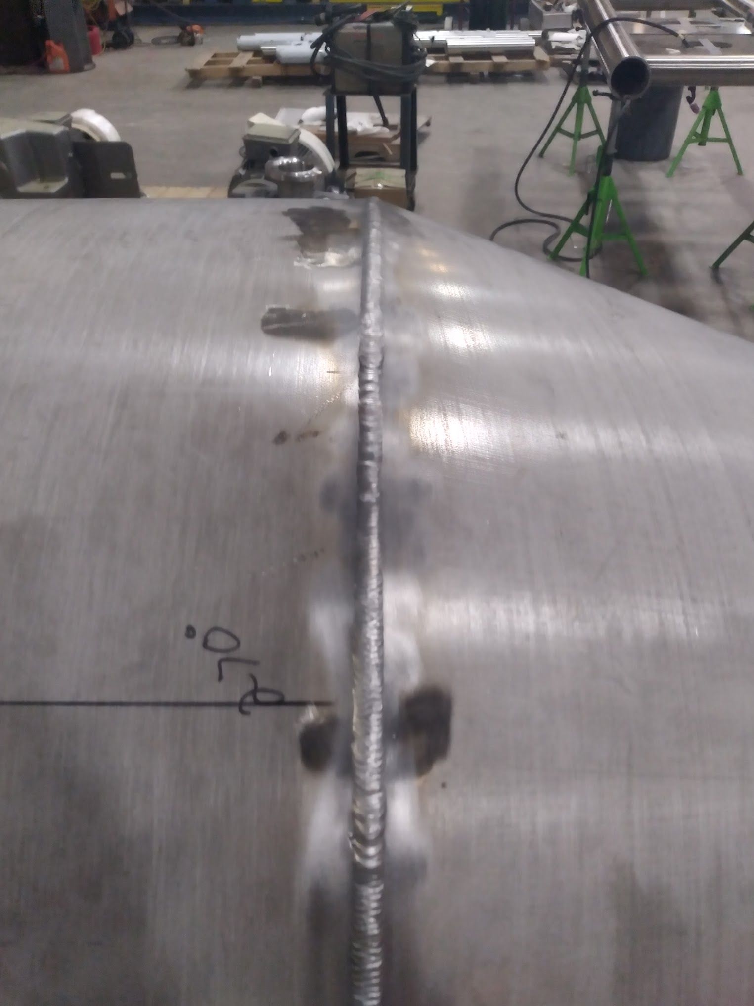A stainless steel pipe is being welded in a factory