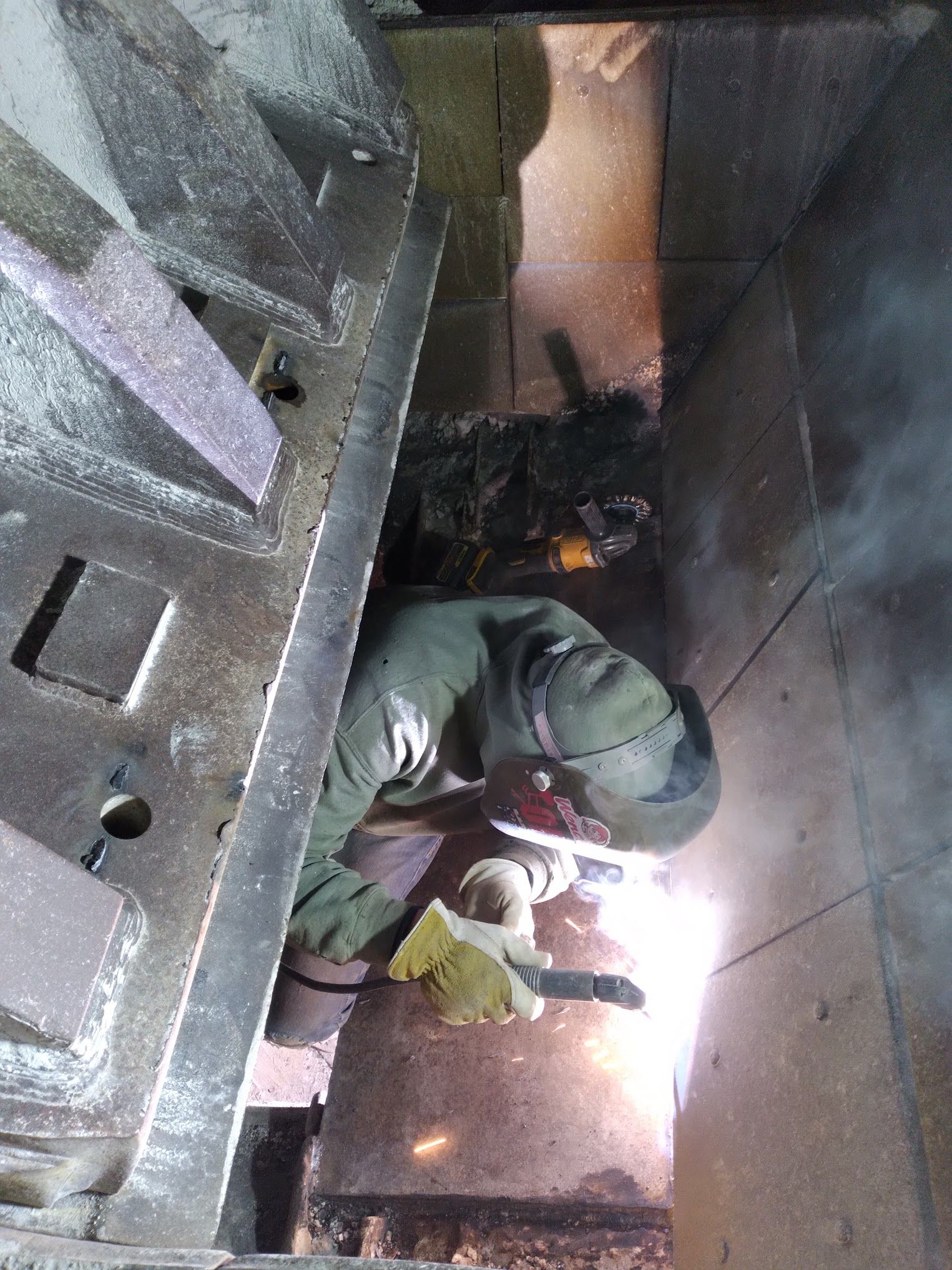 A man is welding a piece of metal in a room.