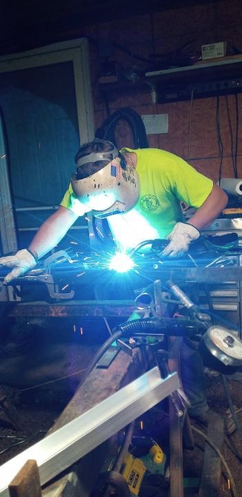 A man is welding a piece of metal in a garage.