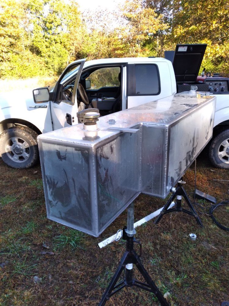 A white truck is parked next to a large metal box on a tripod.