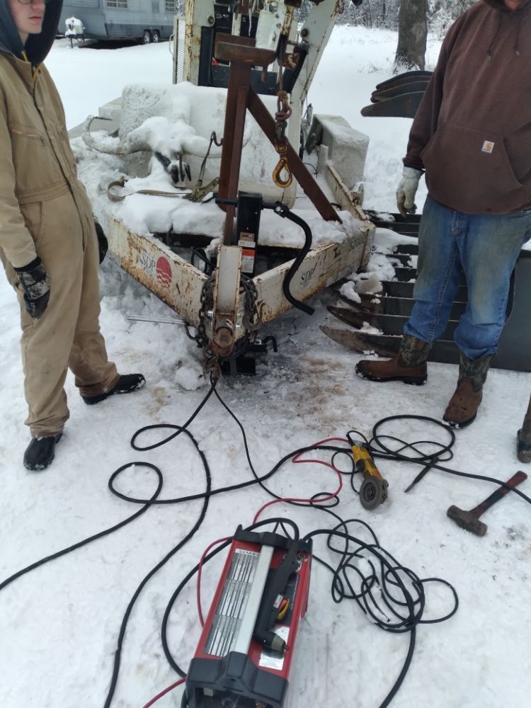 Two men are working on a trailer in the snow