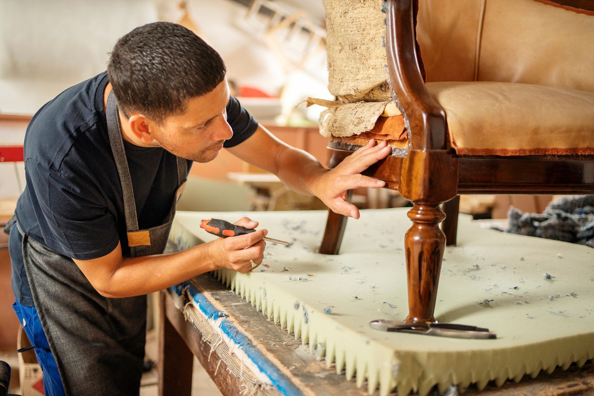 Un hombre está trabajando en una silla en un taller.